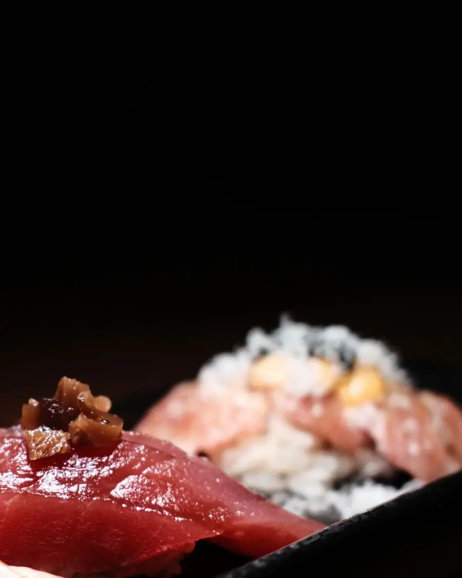 Siyah tabakta akami ve negitoro nigiri; karanlık fon.