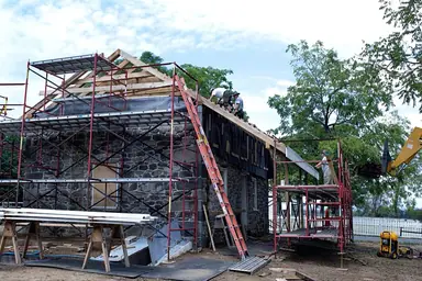 Stone house being re-roofed, with scaffolding and a ladder