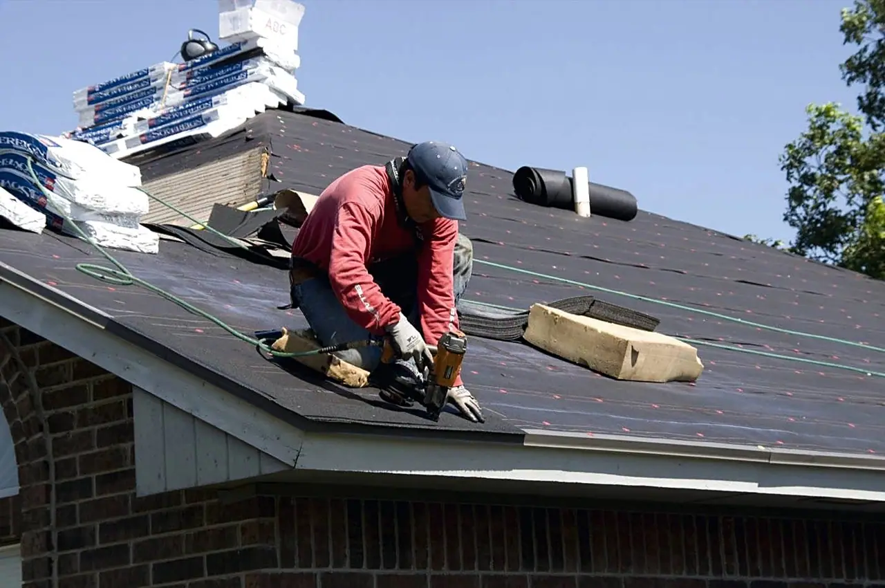 Roofer nailing shingles on a residential deck