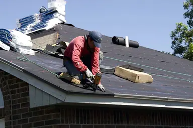 Roofer nailing down a new roof on a house